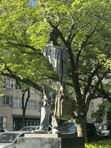 a statue of a man carrying a briefcase stands in front of a tree