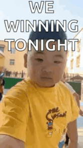 a little boy in a yellow shirt is taking a selfie with the words `` we winning tonight '' written on it .