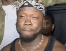 a close up of a man wearing a bandana and a necklace .