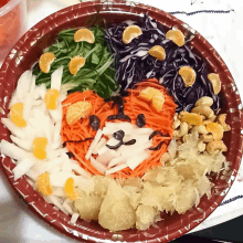 a bowl of fruits and vegetables has a face drawn on it