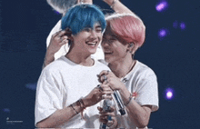 two boys with blue hair are standing next to each other on a stage holding microphones .