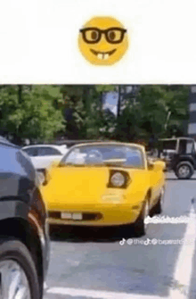 a yellow car with a smiley face on the front is driving down a street .