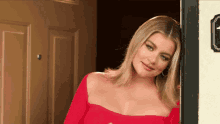 a woman in a red off the shoulder top is standing in front of a door