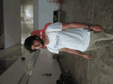 a man wearing a white denim t-shirt stands on a tiled floor