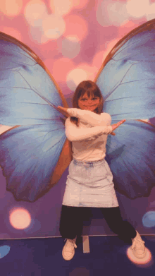 a little girl is standing in front of a butterfly wing