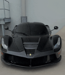 a black ferrari is parked in a garage with a white wall behind it