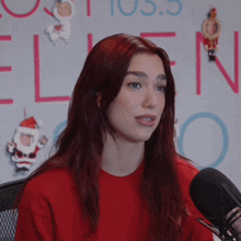 a woman with red hair is sitting in front of a microphone in front of a wall that says ellen on it