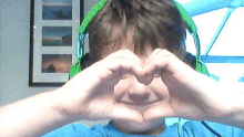 a boy wearing headphones is making a heart shape with his hands