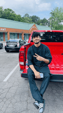 a man is sitting on the back of a red truck in front of a building that says jack grill