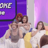 a group of young women are sitting in front of a sign that says oke