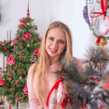 a woman stands in front of a christmas tree with a clock behind her that says xii