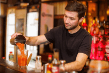 a bartender pours a drink into a glass with a corona fridge in the background