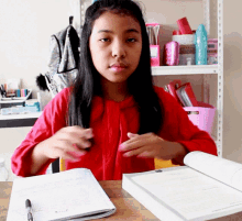 a girl in a red shirt sits at a desk with a book open to a page that says ' a ' on it