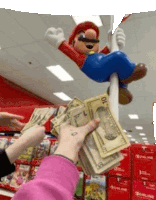 a person is holding a stack of money in front of a mario statue hanging from a pole .