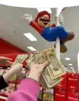 a person is holding a stack of money in front of a mario statue hanging from a pole .