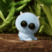 a blue stuffed animal with big eyes is sitting on the ground