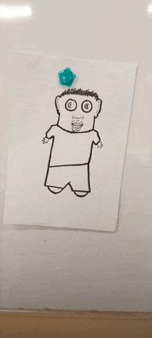 a drawing of a man with a smiley face is pinned to a white board with a blue magnet