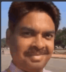 a man with a mustache is smiling for the camera in a close up of his face .