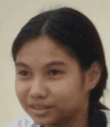 a close up of a young girl 's face with a white shirt on .