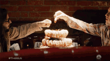 a man and a woman are sitting at a table with a stack of shrimp on it and a nbc logo behind them