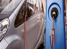 a silver electric car is being charged at a blue charging station .