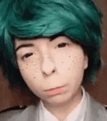 a close up of a person wearing a green wig and a white shirt .