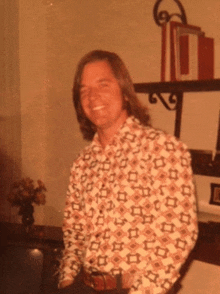 a man wearing a shirt with a pattern of squares is smiling