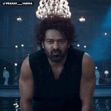 a man with a beard is standing in front of a chandelier with the hashtag pranay varma