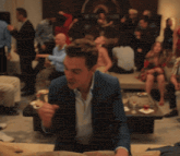a man in a blue suit is sitting in front of a crowd of people