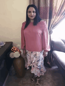 a woman in a pink off the shoulder top stands in front of a couch