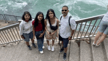 a group of people are standing on a set of stairs near the ocean