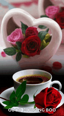 a cup of coffee next to a red rose and a heart shaped vase of roses