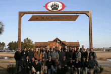 a group of men are posing for a picture in front of a blackwater sign