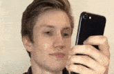 a young man is taking a picture of himself with a cell phone .