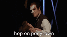 a man with a mask on his face is holding a woman in his arms with the words hop on ponytown in the background
