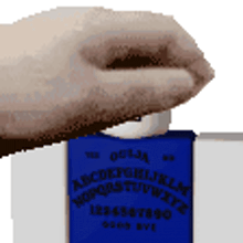 a hand is holding a blue ouija board with the alphabet on it