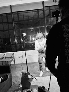 a black and white photo of a man standing in front of a camera wearing a sweatshirt that says ' detroit '