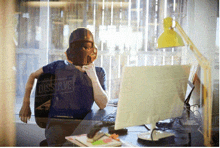 a man wearing a helmet sits at a desk with a computer in front of him