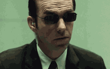 a man in a suit and tie wearing sunglasses and ear buds