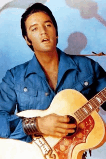 a man wearing a blue shirt is holding a guitar