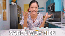 a woman sitting in a kitchen with a tray of macarons and the words saben muy bien on the table