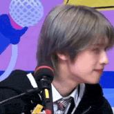 a young man is sitting in front of a microphone .