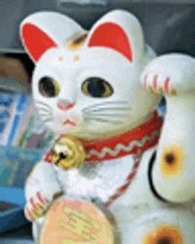 a statue of a white cat with red ears and a bell around its neck .