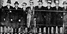 a group of men in suits and hats are standing in a line