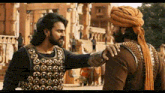 two men are standing next to each other and one of them is wearing a turban .