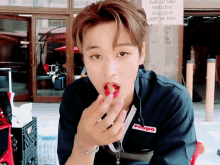 a young man eating a strawberry in front of a sign that says hard hat area protective headgear must be worn