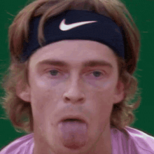 a man wearing a headband and a nike headband is sticking his tongue out .