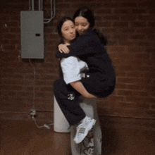 a woman is carrying another woman on her back with the letter a on her sweatpants