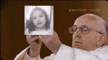 a man in glasses is holding a picture of a woman