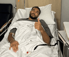 a man in a hospital bed giving a thumbs up sign